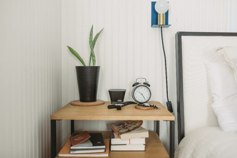 plant and clock on nightstand next to bed