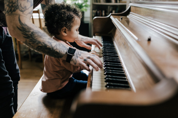 father playing with baby on piano
