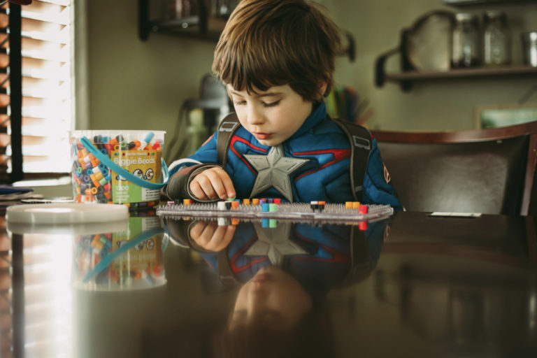 Little boy in a superhero costume counting candy at a table.