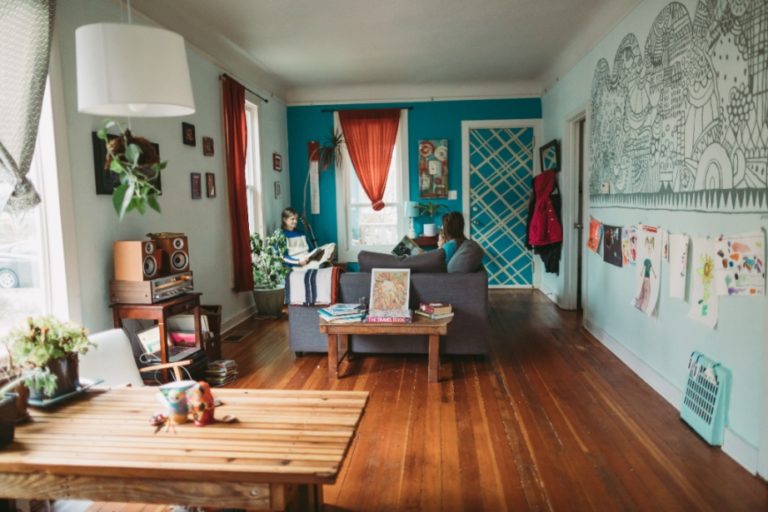 Family hanging out in bright, colorful living room with child's artwork hanging on walls.