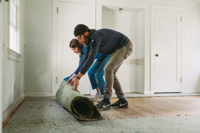 Man and woman ripping up carpet during home renovation.