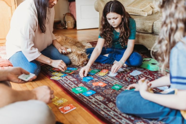 Woman playing a game with kids on the living room floor.