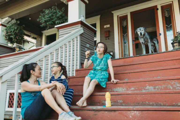Family hanging out with their dog on their porch.