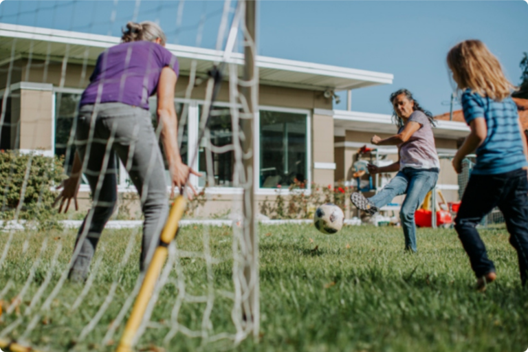 Family playing soccer on a sunny day.