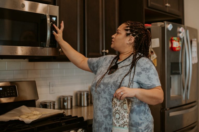 Woman putting food in the microwave in her kitchen.