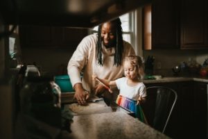 Little girl helps woman bake in a kitchen.